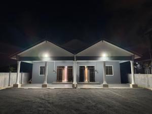 a white house with two doors at night at Homestay De Acacia Rumah Melati in Kuala Terengganu