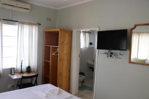a bedroom with a bed and a television on a wall at Joyful Vista Guest Lodge in Victoria Falls