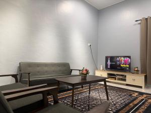a living room with a couch and a tv at Homestay De Acacia Rumah Melati in Kuala Terengganu