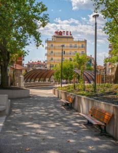 a park with two benches in front of a building at Anesis Hotel in Kozani