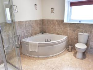 a bathroom with a white tub and a toilet at Braehouse cottage in Kilmory