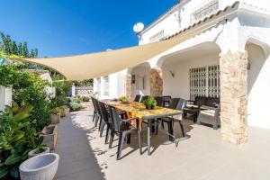 a patio with a table and chairs under an umbrella at Piscina, mar y centro – Casa ideal para familias in Empuriabrava