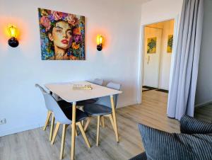 a dining room with a table and chairs and a painting at Panorama-Meerblick am Scharbeutzer Strand in Scharbeutz