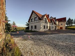 a large white building on a gravel road at Agroturystyka Kaczor nad jeziorem in Męcidół
