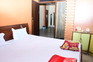 a bedroom with a white bed with a red bag on it at Hotel Sampark in Bhadrak