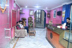two people sitting in a room with pink walls at Hotel Sampark in Bhadrak
