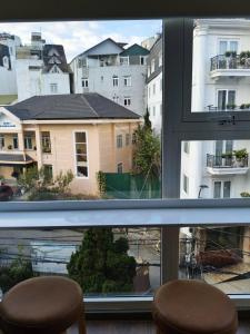 a view of a city from a window with two stools at The Cloud Hotel in Da Lat