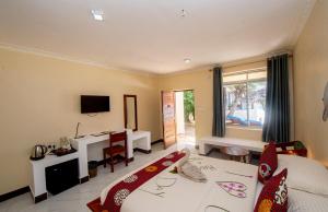 a bedroom with a bed and a desk and a television at Double A Nungwi Beach Hotel - Beach Front in Nungwi