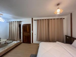 a bedroom with a bed and a table and curtains at บ้านซินอัน in Ban Rak Thai +10 photos