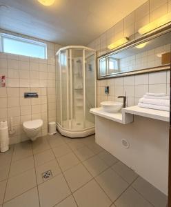 a bathroom with a shower and a toilet and a sink at Hótel Dalvík in Dalvík +139 photos