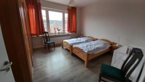 a bedroom with a bed and a window with red curtains at Ferienwohnung Möwe in Dornum