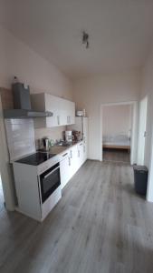 a kitchen with white cabinets and a wooden floor at Ferienwohnung Möwe in Dornum