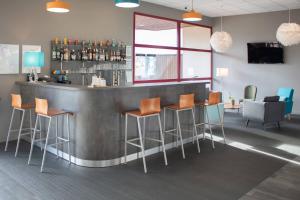 eine Bar mit orangefarbenen Hockern in einem Raum in der Unterkunft Brit Hotel Bressuire in Bressuire