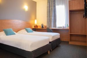 ein Hotelzimmer mit zwei Betten und einem Schreibtisch in der Unterkunft Brit Hotel Bressuire in Bressuire + 50 Fotos