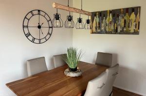 a dining room with a table with chairs and a clock at Ferienhaus Kompassqualle in Dornumersiel