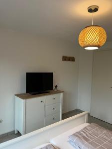 a room with a tv on a dresser with a television at Ferienhaus Kompassqualle in Dornumersiel