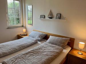a bedroom with two beds and two windows at Ferienhaus Kompassqualle in Dornumersiel
