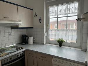 a kitchen with a window and a sink and a stove at Ferienhaus Kompassqualle in Dornumersiel +14 photos