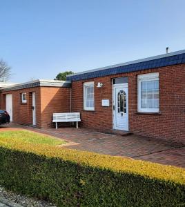 a brick house with a bench in front of it at Ferienhaus Kompassqualle in Dornumersiel