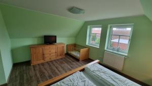 a bedroom with a bed and a tv on a dresser at Ferienhaus Sommerwind in Neßmersiel