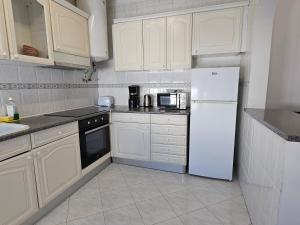 a kitchen with white cabinets and a white refrigerator at Blife Martya apartment in Olhão +26 photos
