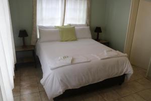 a bed with white sheets and pillows and a window at Joyful Vista Guest Lodge in Victoria Falls