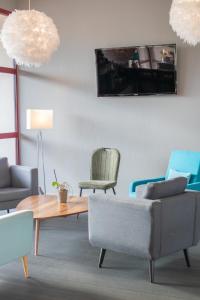 ein Wohnzimmer mit Stühlen, einem Tisch und einem Sofa in der Unterkunft Brit Hotel Bressuire in Bressuire