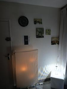 a room with a clock on the wall and a refrigerator at Chambre double avec lit clic clac in Saint-Pardoux-Isaac