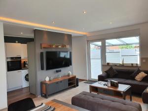 a living room with a couch and a flat screen tv at Ferienhaus Wiesenpieper in Dornum