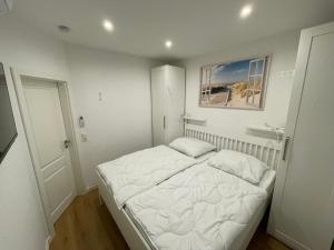 a small white bedroom with a bed and a sink at Ferienhaus Margarete in Dornumersiel