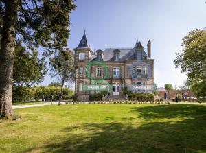 an old house with a large grassy field in front at Le Château des Tourelles en Vendée in La Gaubretière