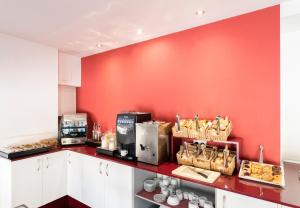 a kitchen with a red wall and a counter with food at Soho Boutique Salamanca in Salamanca