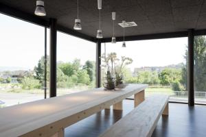 a long wooden table in a room with large windows at Hotel am Garnmarkt in Götzis