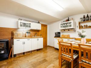 a kitchen with white cabinets and a table with chairs at Chalupa Sibřinka in Korkusova Huť