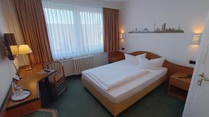 a hotel room with a large bed and a desk at LAT Hotel & Apartmenthaus Berlin in Eisenhüttenstadt
