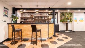 a bar with two stools in a room at Kyriad Direct Limoges Nord in Limoges