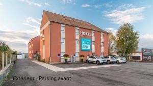 a building with cars parked in a parking lot at Kyriad Direct Limoges Nord in Limoges