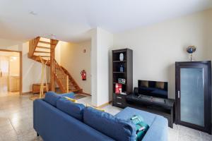 a living room with a blue couch and a tv at Santana Lens & Trail House in Santana