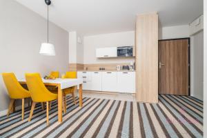 a kitchen and dining room with a table and yellow chairs at Your Holidays Bel Mare II D105 in Międzyzdroje