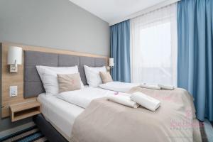a bedroom with two beds with blue curtains and a window at Your Holidays Bel Mare II D105 in Międzyzdroje +19 photos