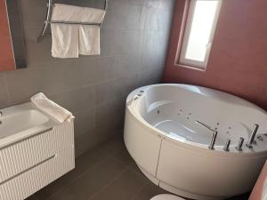 a white bathroom with a tub and a sink at VISAJ Jacuzzi Romantic in Timişoara