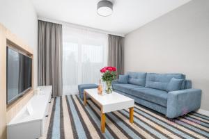 a living room with a blue couch and a tv at Your Holidays Bel Mare II D105 in Międzyzdroje