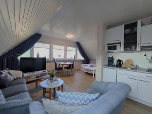 a living room with blue couches and a kitchen at Gästehaus Schuppe in Tarp in Tarp