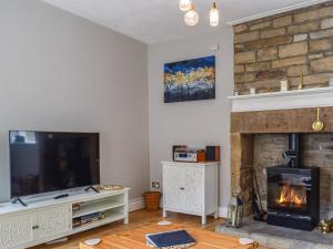 a living room with a fireplace and a tv at St Georges Cottage in Holmfirth