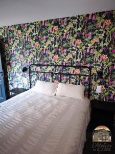 a bedroom with a bed with a floral wallpaper at L'Atelier de Claude in Wattwiller
