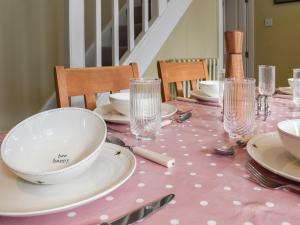 a table with plates and glasses on a pink table cloth at St Georges Cottage in Holmfirth +16 photos