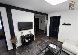 a living room with a television and a couch at L'Atelier de Claude in Wattwiller