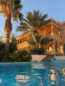 a house with palm trees in front of a swimming pool at Maroccana in Dobra Voda