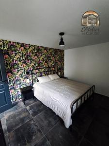 a bedroom with a large bed with a wall covered in flowers at L'Atelier de Claude in Wattwiller +6 photos