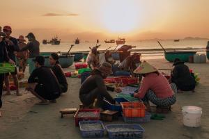 a group of people sitting on the beach eating food at Thiện Homestay Dốc Lết -Gần Biển & Nguyên Căn in Ba Ha